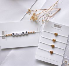 the name bride spelled with beads and hearts on a white card next to some flowers