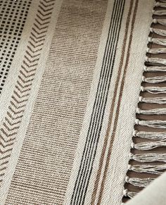 a brown and white striped blanket with fringes on the bottom, next to a black and white checkered table cloth