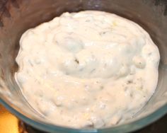 a bowl filled with white sauce sitting on top of a table next to an orange