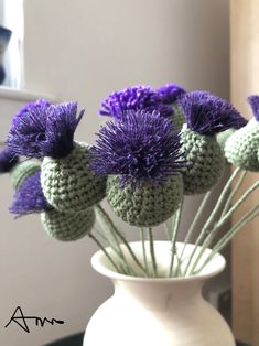 a white vase filled with purple flowers on top of a table