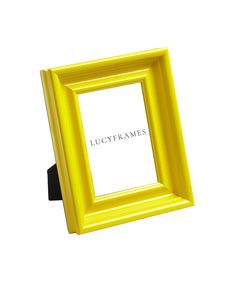 a yellow frame sitting on top of a white wall next to a black object with the word lucgyframes written in it