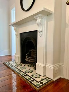 a fireplace with a mirror on the wall above it and wood flooring in front of it