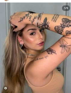 a woman with many tattoos on her arm and shoulder, looking at the camera while holding her hand behind her head