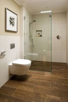 a bathroom with wood flooring and white walls, including a toilet and walk in shower