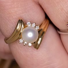 This romantic ring features a lustrous pearl accented by diamonds in a dynamic bypass design. The high quality diamonds add bright sparkle to the sweet romance of the pearl. The effect is an air of grace and timeless elegance. This beauty would make an excellent anniversary gift or a beautiful treat for yourself!The pearl is spherical and has beautiful luster. It is securely attached to the setting. The diamonds are all brilliantly white, graded G for color. They are all completely eye clean, gr Fine Jewelry Brilliant Cut Pearl Ring For Anniversary, Fine Jewelry Pearl Ring With Single Diamond For Anniversary, Fine Jewelry Pearl Ring With Diamond Accents For Anniversary, Timeless Pearl Ring With Diamond Accents For Anniversary, Timeless Anniversary Pearl Ring With Diamond Accents, Anniversary Yellow Gold Pearl Ring With Diamond, Anniversary Akoya Pearl Yellow Gold Ring, Elegant Diamond White Bypass Ring For Anniversary, Yellow Gold Rings With Diamond Accents And Pearl