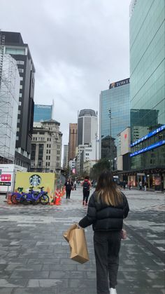 a woman is walking down the street carrying shopping bags in her hand and looking at buildings