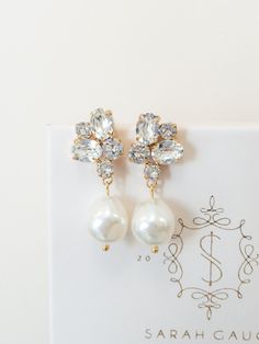 a pair of pearl and crystal earrings on top of a white card with the name sarah caug written in gold