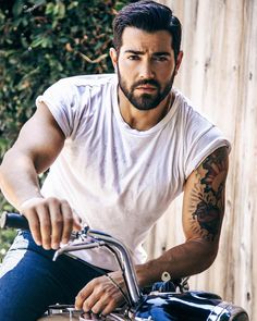 a man with tattoos on his arm riding a motorcycle