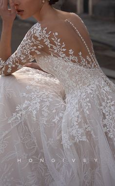 a woman in a wedding dress sitting on the ground with her hand to her face