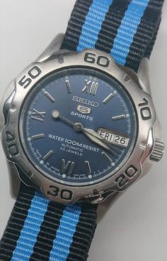 A great Seiko 5 Sports watch 7S36-00A0, fully serviced and tested.  - Serviced and tested Seiko 7s36 automatic movement, running well within the manufacturers specified +/- 30 seconds per day for this calibre (note this movement cannot be manually wound, it is automatic wind only)  - Lovely blue dial - On a new NATO style black & blue striped strap - Polished/brushed finished fixed bezel with brushed finish Stainless Steel case, measuring approx 41mm in diameter including the crown - Nice clean Classic Sports Watch With Round Dial, Automatic Chronograph Sports Watch With Round Dial, Sports Automatic Watches With Round Dial, Automatic Sports Watches, Sports Automatic Watches, Blue Sporty Outdoor Watch, Sporty Blue Outdoor Watch, Blue Sports Watch With Round Dial, Blue Sports Watches With Analog Display