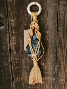 a rope hanging on the side of a wooden wall with a blue stone and white ring