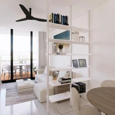 a living room filled with furniture and bookshelves next to a dining table on top of a hard wood floor