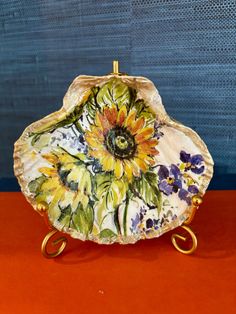 an ornately decorated platter with flowers on the bottom and gold handles sits on a red surface