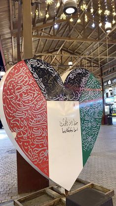 a large heart shaped sculpture in the middle of a building with arabic writing on it