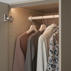 an open closet with clothes hanging on hooks