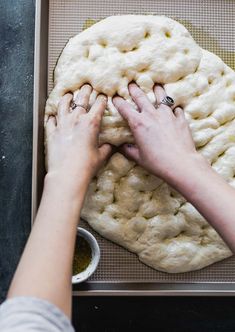 two hands on top of a pizza dough