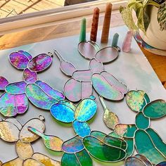 stained glass pieces are displayed on a table next to candles and potted plant in the background