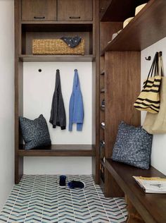 a coat closet with two coats hanging on the wall and one pair of slippers laying on the floor