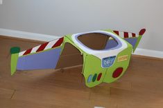 a cardboard box shaped like a green airplane with red and white stripes on the side