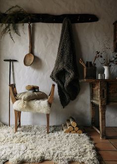 a chair sitting in front of a wall with pots and pans hanging on it