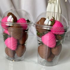 two plastic cups filled with chocolate covered strawberries and pink flowers on top of each other