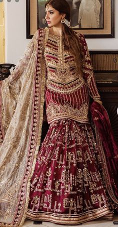 a woman in a red and gold bridal gown standing next to a painting on the wall