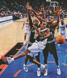 the basketball players are trying to block the ball from going into the basket in front of them