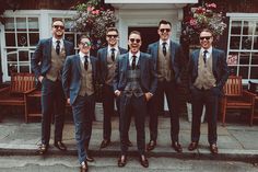 a group of men standing next to each other wearing suits and ties on the street