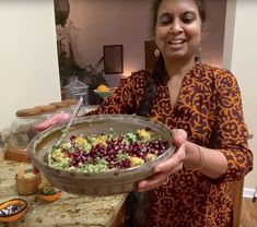 a woman holding a platter full of fruit salad