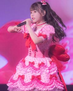 a girl in a pink dress holding a microphone