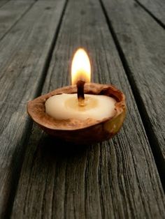 a lit candle sitting inside of a wooden container on top of a wooden table next to a piece of wood