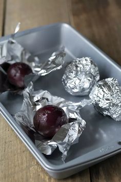 three pieces of tin foil sitting on top of a metal pan filled with cherries