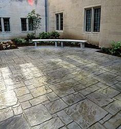 a white bench sitting in the middle of a courtyard next to a building with windows