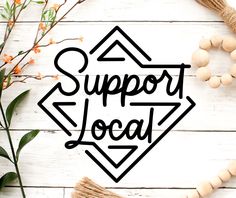 the word support local is surrounded by flowers and other items on a white wooden surface