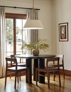 a dining room table with two chairs and a vase on the table in front of it