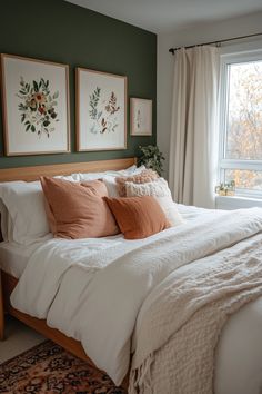 a bedroom with green walls, white bedding and two framed pictures on the wall