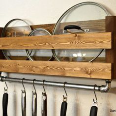 a wooden rack with pots and pans hanging from it's sides, holding utensils