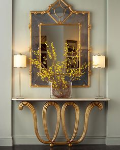 a vase with yellow flowers sitting on top of a table in front of a mirror