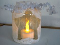 a lit candle in a glass jar on a table