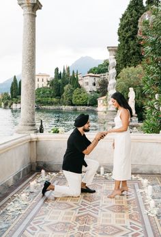 a man kneeling down next to a woman who is touching her hand on the ground