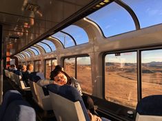 there are many people sitting on the train looking out the windows at the desert landscape