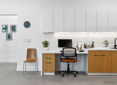 an office desk with a computer on top of it next to a chair and clock