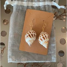 two seashells are sitting on a piece of paper next to a pair of earrings