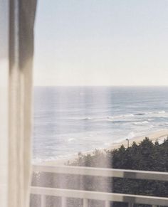 an ocean view from the window of a hotel room with a balcony overlooking the beach