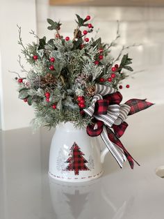 a christmas arrangement in a white vase on a table