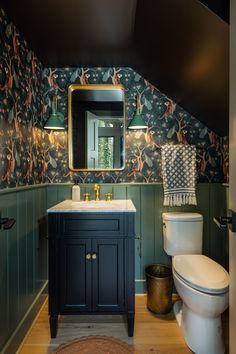 a bathroom with a toilet, sink and mirror in it's center wallpaper