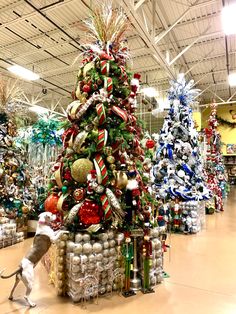 a christmas tree in a store with lots of ornaments on it and a dog standing next to it