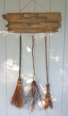 three brooms hanging from a wooden sign that says broom parking