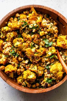 a wooden bowl filled with roasted cauliflower and chickpeas