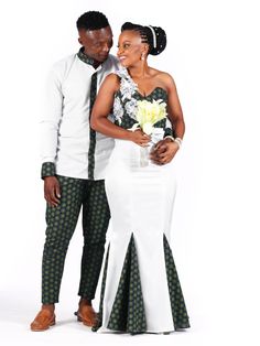 a man and woman standing next to each other in front of a white background wearing african clothing